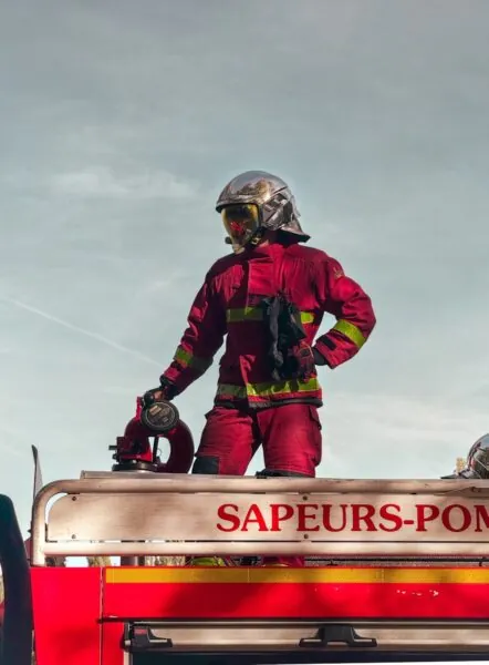 A fireman standing on top of a fire truck