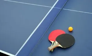 two ping pong paddles and a ping pong ball on a blue table